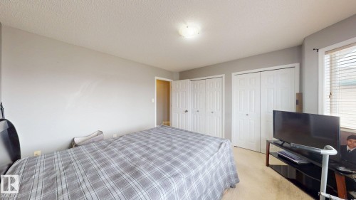 This room features a neutral color palette, two sets of bi-fold closet doors, and window blinds - 5929 8 Avenue, Edmonton, AB - Indoor Photo Showing Bedroom