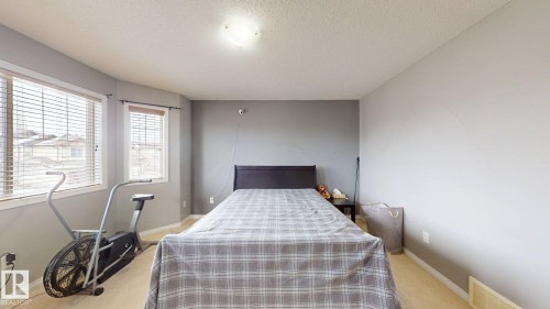 This room features neutral-toned walls, a textured ceiling, and carpeted flooring - 5929 8 Avenue, Edmonton, AB - Indoor Photo Showing Bedroom