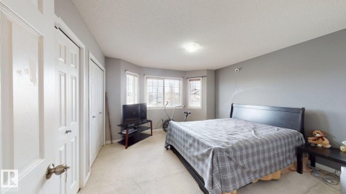 This bedroom features light-colored carpeting, a light gray painted wall, and a bay window providing natural light - 5929 8 Avenue, Edmonton, AB - Indoor Photo Showing Bedroom