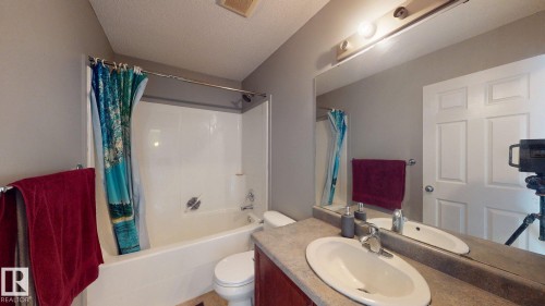The bathroom features a vanity with a countertop and an oval sink, a mirror with overhead lighting, and a bathtub with a shower - 5929 8 Avenue, Edmonton, AB - Indoor Photo Showing Bathroom