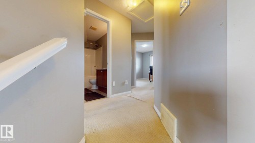 Hallway with light-colored carpeting, white baseboards, and a white handrail - 5929 8 Avenue, Edmonton, AB - Indoor Photo Showing Other Room