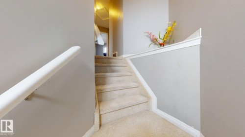 Carpeted staircase featuring a white handrail and white trim detailing - 5929 8 Avenue, Edmonton, AB - Indoor Photo Showing Other Room