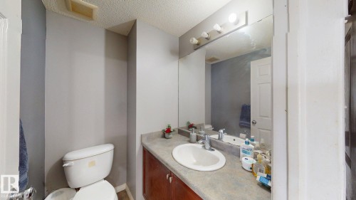 Bathroom featuring a vanity with an integrated sink, a large mirror, and a toilet - 5929 8 Avenue, Edmonton, AB - Indoor Photo Showing Bathroom