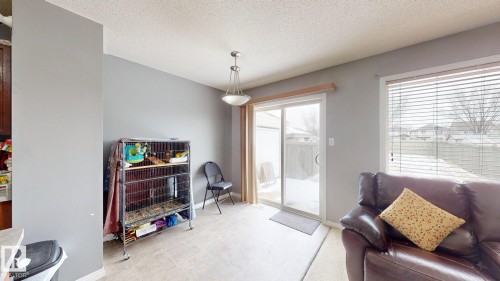This area features light-colored flooring, a sliding glass door providing access to the outdoors, and a window with blinds overlooking the exterior - 5929 8 Avenue, Edmonton, AB - Indoor