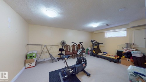 The property features an extensive room with light-colored walls and carpeting, offering a versatile space - 5929 8 Avenue, Edmonton, AB - Indoor Photo Showing Gym Room