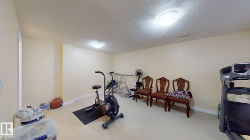 This versatile room features neutral-toned walls, carpeted flooring, and overhead lighting, creating an adaptable space - 5929 8 Avenue, Edmonton, AB - Indoor Photo Showing Gym Room