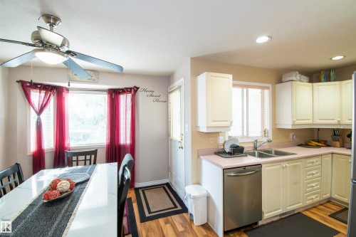 The kitchen features cream cabinetry, stainless steel appliances, and a double basin sink, with recessed lighting throughout - 2 9703 174 Street, Edmonton, AB - Indoor