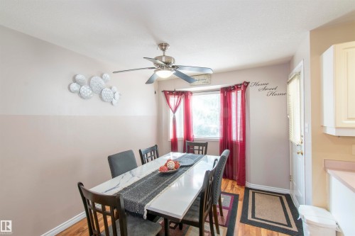 Dining area featuring wood-look flooring, a ceiling fan, and a window with red curtains - 2 9703 174 Street, Edmonton, AB - Indoor Photo Showing Dining Room