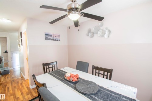 The property features a dining area with a ceiling fan, a wall with a two-tone paint scheme, and laminate flooring visible in the entry - 2 9703 174 Street, Edmonton, AB - Indoor Photo Showing Dining Room