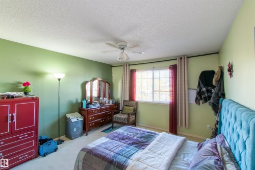 This property features a room with light green walls, a window with vertical blinds and curtains, and a ceiling fan - 2 9703 174 Street, Edmonton, AB - Indoor Photo Showing Bedroom