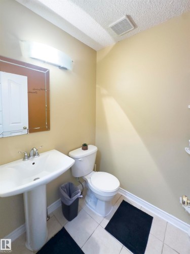 The bathroom includes a pedestal sink with a chrome faucet, a toilet, and light-toned wall paint - 2 9703 174 Street, Edmonton, AB - Indoor Photo Showing Bathroom