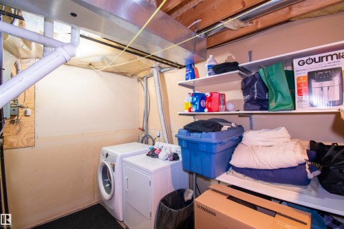 The property features a dedicated laundry area equipped with a washing machine and dryer, complemented by overhead shelving for storage - 2 9703 174 Street, Edmonton, AB - Indoor Photo Showing Laundry Room
