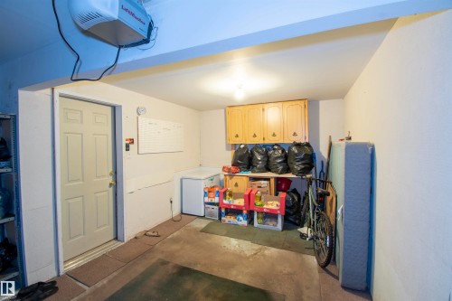 The property features a functional garage space with a garage door opener and overhead cabinetry - 2 9703 174 Street, Edmonton, AB - Indoor
