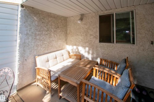 The property features an exterior patio with textured stucco walls and a white slatted ceiling - 2 9703 174 Street, Edmonton, AB - Outdoor With Deck Patio Veranda With Exterior