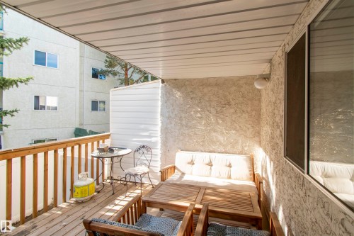 This property features a covered outdoor patio area with a wood-planked floor and a wooden railing - 2 9703 174 Street, Edmonton, AB - Outdoor With Deck Patio Veranda With Exterior
