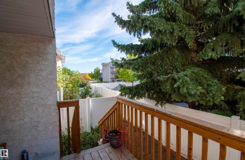 The property features a private deck with wooden railings and steps, surrounded by a white privacy fence - 2 9703 174 Street, Edmonton, AB - Outdoor