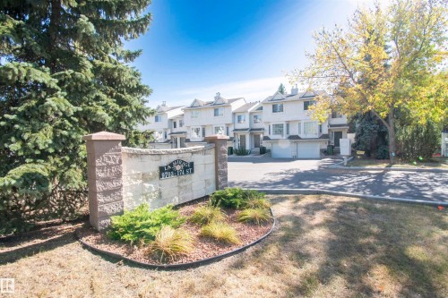 The property features a stone and concrete entrance sign, surrounded by landscaping with shrubs and groundcover - 2 9703 174 Street, Edmonton, AB - Outdoor