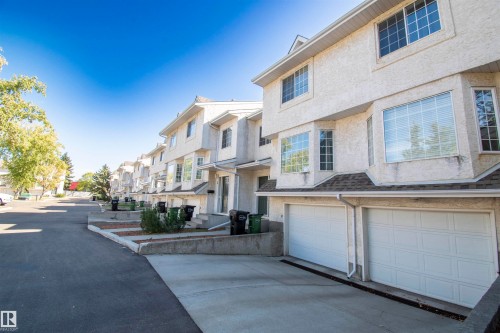 The property features a textured exterior finish and an attached garage with a white door - 2 9703 174 Street, Edmonton, AB - Outdoor