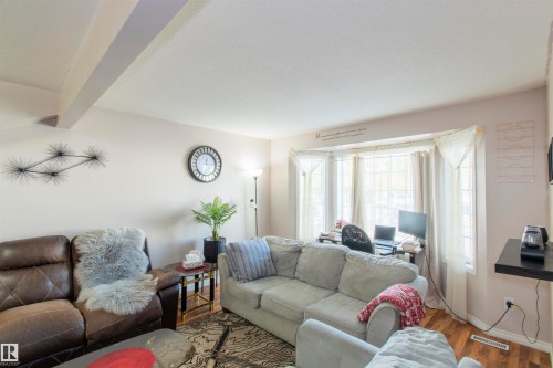 Living area featuring a bay window, hardwood floors, and a decorative ceiling beam - 2 9703 174 Street, Edmonton, AB - Indoor Photo Showing Living Room