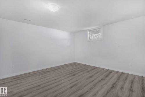 This room features light-toned flooring, white walls, and a window with a lattice-style grate - 12002 37 Street, Edmonton, AB - Indoor Photo Showing Other Room