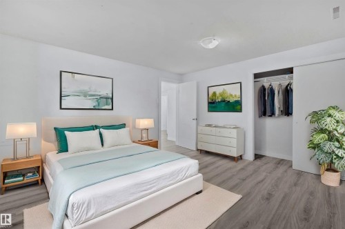 This bedroom features light-colored walls and grey wood-style flooring - 12002 37 Street, Edmonton, AB - Indoor Photo Showing Bedroom