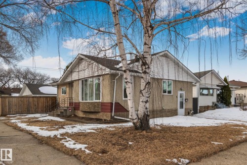 The property features a stucco exterior with a pitched roof, a bay window, and a white front door - 12002 37 Street, Edmonton, AB - Outdoor
