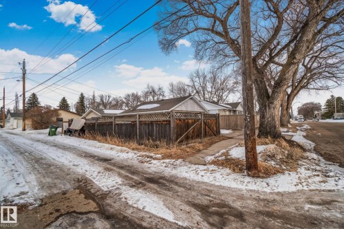 The property features a wooden fence, a detached structure with a pitched roof, and a paved path - 12002 37 Street, Edmonton, AB - Outdoor