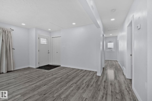 The property features light gray wood-style flooring, white walls, and recessed lighting throughout - 12002 37 Street, Edmonton, AB - Indoor Photo Showing Other Room