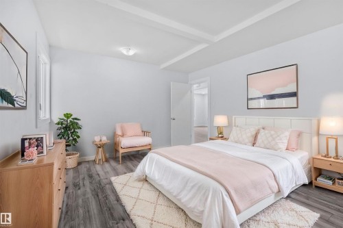 This room features hardwood-style flooring, light-colored walls, and a tray ceiling - 12002 37 Street, Edmonton, AB - Indoor Photo Showing Bedroom