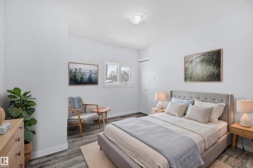 Bedroom featuring light grey walls, grey wood-look flooring, a window, and a closet with bifold doors - 12002 37 Street, Edmonton, AB - Indoor Photo Showing Bedroom