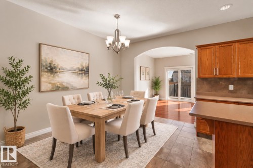 The dining area features a light-toned wooden table with upholstered chairs, set on a patterned area rug - 16419 53 Street, Edmonton, AB - Indoor Photo Showing Dining Room
