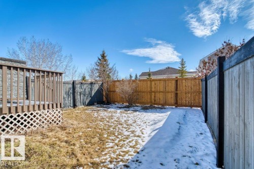 The property features an outdoor deck with lattice skirting, a fenced yard with a mix of wood and stained fences, and a lawn area - 16419 53 Street, Edmonton, AB - Outdoor