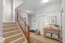 Entryway featuring a carpeted staircase with a wood and wrought iron railing, a front door with decorative glass, and a tiled floor - 16419 53 Street, Edmonton, AB  - Indoor Photo Showing Other Room 