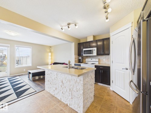 The property features a kitchen with dark cabinetry, light countertops, and a white backsplash - 9073 Scott Crescent, Edmonton, AB - Indoor Photo Showing Kitchen