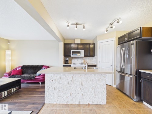 The kitchen features dark wood cabinetry, stainless steel appliances, and a tiled backsplash - 9073 Scott Crescent, Edmonton, AB - Indoor Photo Showing Kitchen