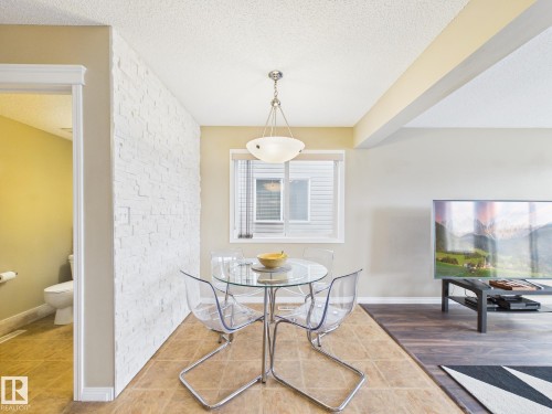 Dining area featuring tile flooring, a window with blinds, and a modern light fixture - 9073 Scott Crescent, Edmonton, AB - Indoor Photo Showing Dining Room