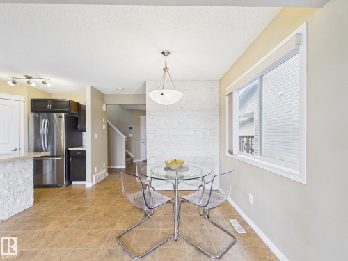 The dining area features a decorative light fixture, a window with blinds, and tile flooring - 9073 Scott Crescent, Edmonton, AB - Indoor