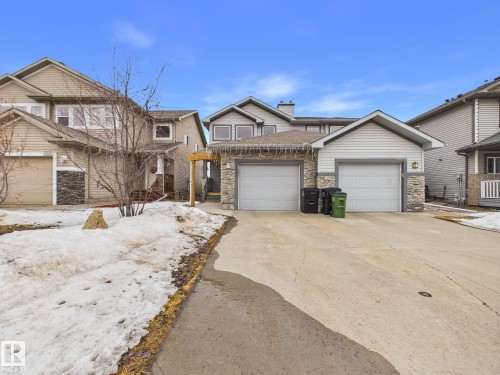 The property features a two-car garage with a concrete driveway, stone accents, and siding exterior - 9073 Scott Crescent, Edmonton, AB - Outdoor With Facade