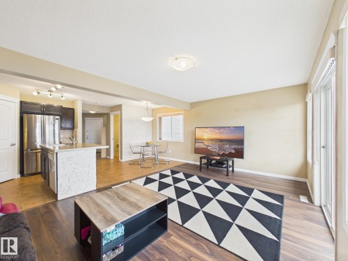 The property features an open-concept living area with hardwood flooring, a kitchen island with stone detailing, and stainless steel appliances - 9073 Scott Crescent, Edmonton, AB - Indoor