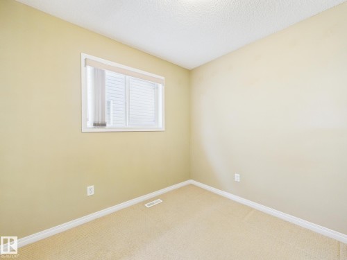 This room features light-colored carpet flooring, a window with blinds, and white baseboards - 9073 Scott Crescent, Edmonton, AB - Indoor Photo Showing Other Room