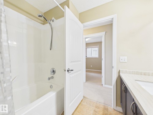 Bathroom featuring a shower and bathtub combination with a chrome showerhead and fixtures, a vanity with a light-colored countertop, and a white door with a silver handle - 9073 Scott Crescent, Edmonton, AB - Indoor Photo Showing Bathroom