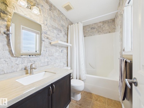 Bathroom featuring a dark wood vanity with a light-colored countertop, an undermount sink, and a silver faucet - 9073 Scott Crescent, Edmonton, AB - Indoor Photo Showing Bathroom