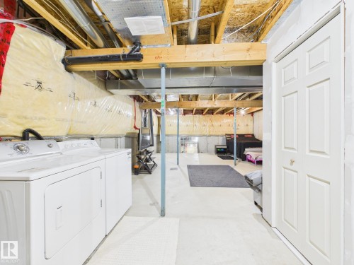 The lower level features exposed wooden beams, a washer and dryer, and a storage closet with a white paneled door - 9073 Scott Crescent, Edmonton, AB - Indoor Photo Showing Laundry Room