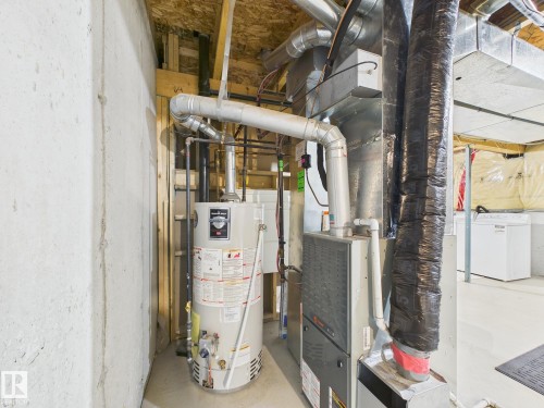 The property includes a water heater and furnace, with exposed ductwork and concrete walls - 9073 Scott Crescent, Edmonton, AB - Indoor Photo Showing Basement