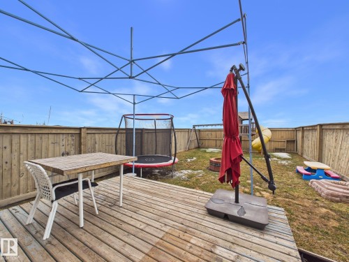 The property features a wooden deck with a table and chair, offering direct access to a fenced yard - 9073 Scott Crescent, Edmonton, AB - Outdoor With Deck Patio Veranda