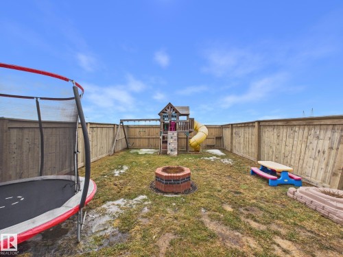The property features a fenced backyard with a grass lawn and a brick fire pit - 9073 Scott Crescent, Edmonton, AB - Outdoor