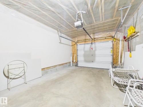 The garage features a concrete floor, a white overhead door, and an automatic garage door opener - 9073 Scott Crescent, Edmonton, AB - Indoor Photo Showing Garage