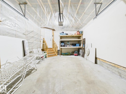 This spacious garage features a concrete floor, built-in wooden shelving for storage, and exposed ceiling joists - 9073 Scott Crescent, Edmonton, AB - Indoor