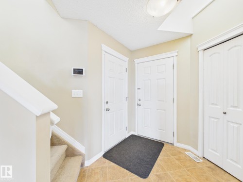Inviting entryway featuring tile flooring, neutral wall colors, a white paneled door, and a staircase with carpeted treads - 9073 Scott Crescent, Edmonton, AB - Indoor Photo Showing Other Room