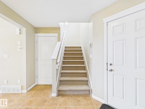 Entryway featuring a carpeted staircase with white railings, paneled doors, and tiled flooring - 9073 Scott Crescent, Edmonton, AB - Indoor Photo Showing Other Room